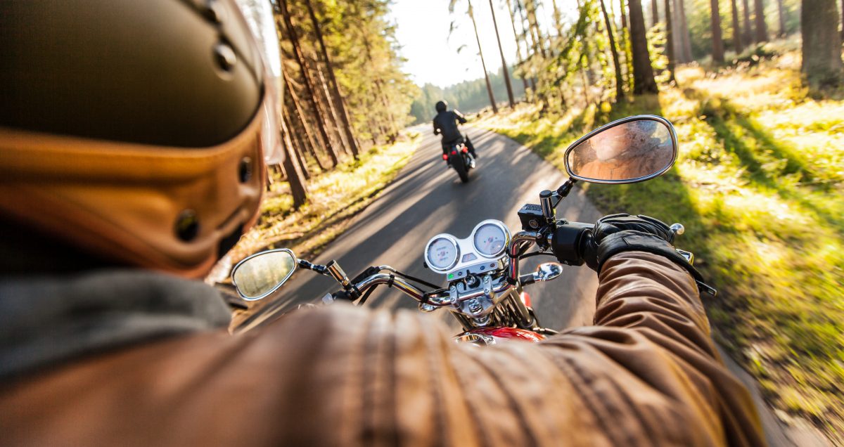 Man seat on the motorcycle on the forest road during sunrise.