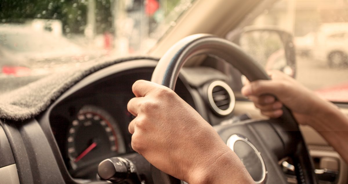 hands on steering wheel of car driving in vintage color tone