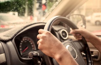 hands on steering wheel of car driving in vintage color tone