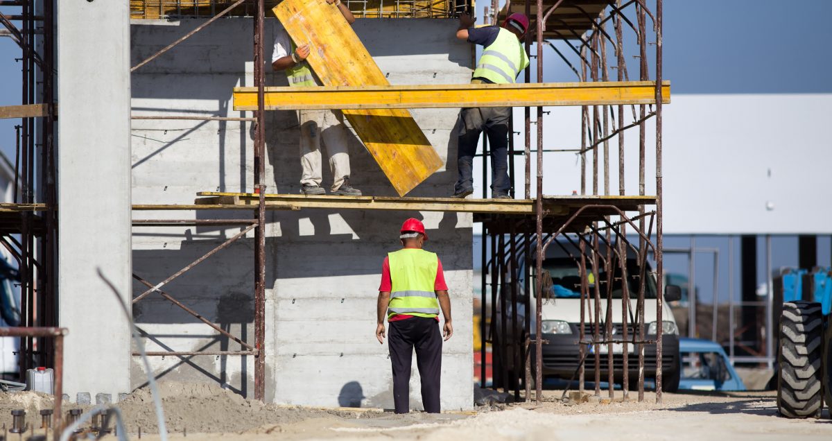 Team work at construction site, workers passing metal formworks on scaffolds