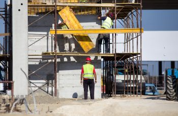 Team work at construction site, workers passing metal formworks on scaffolds