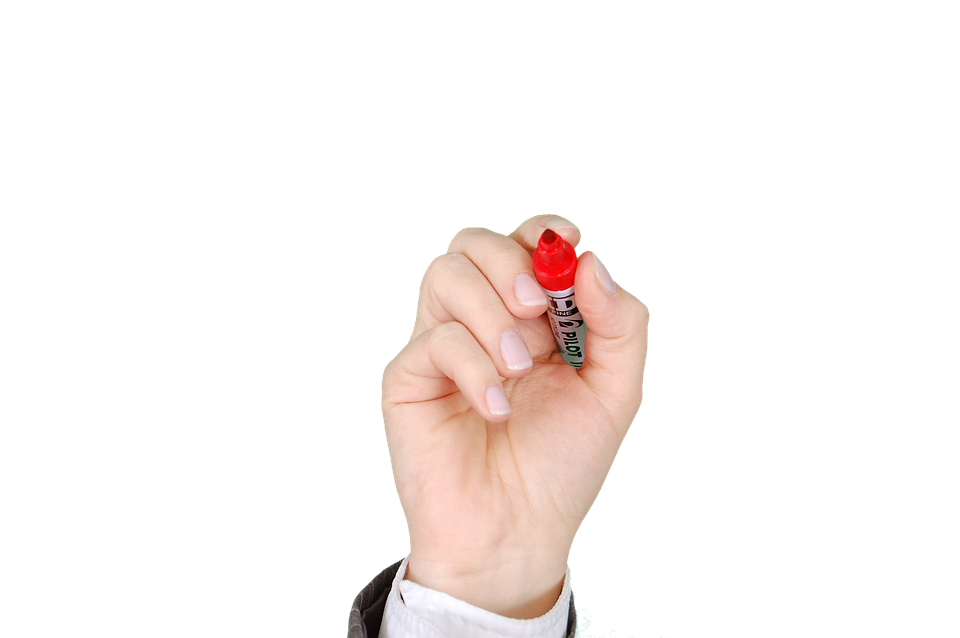 A hand holding a red pen and writing on a whiteboard