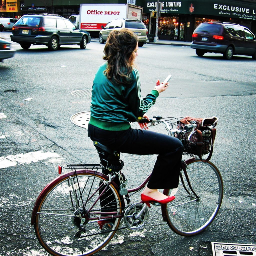 Woman on bike stopped and texting in the middle of the road