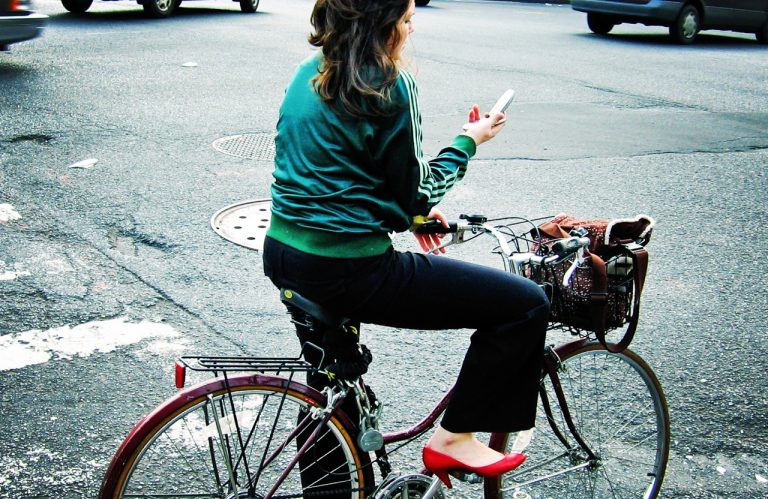 Woman on bike stopped and texting in the middle of the road