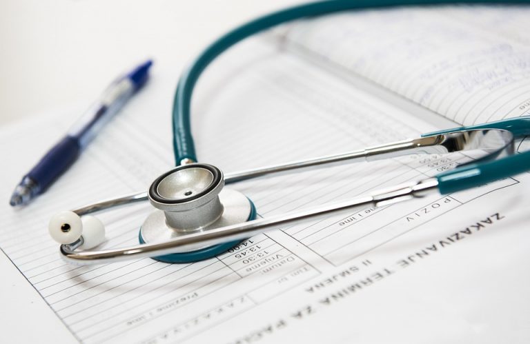 A stethoscope and a pen laying on top of medical papers