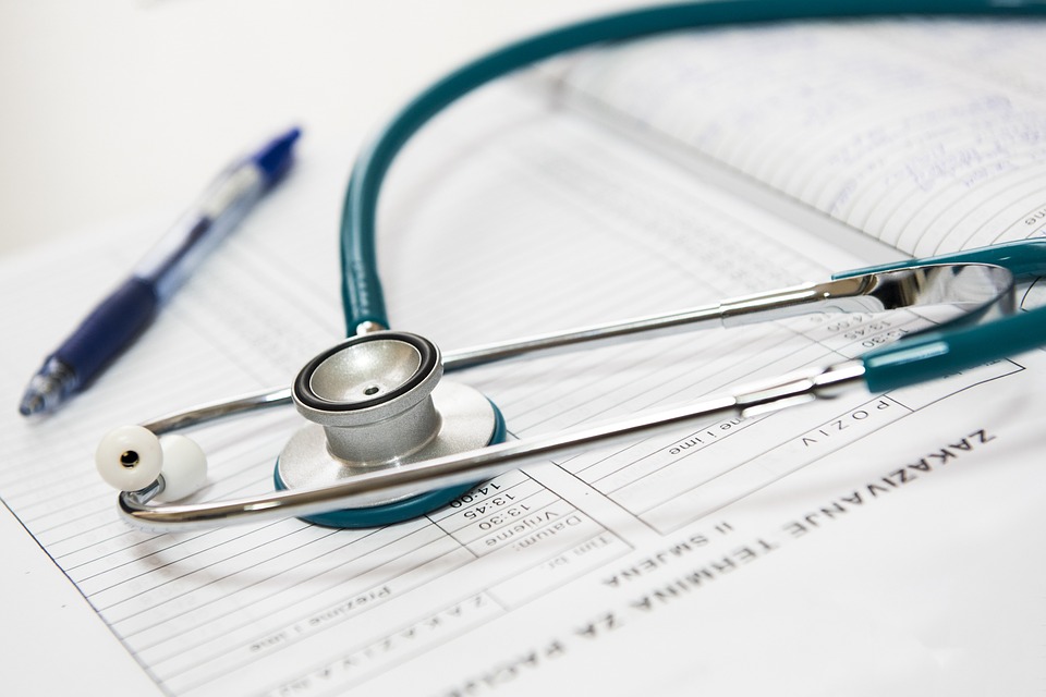 A stethoscope and a pen laying on top of medical papers