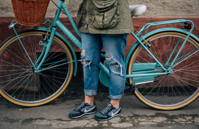 Woman in jeans standing next to a blue bike