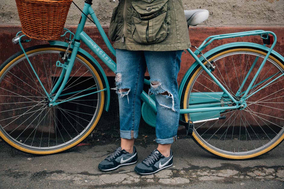 Woman in jeans standing next to a blue bike