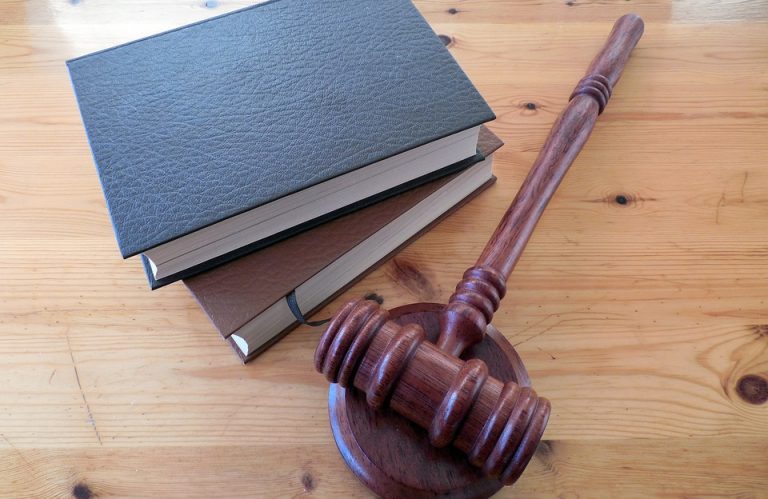 A gavel resting beside two books, pictured to reference the recent rulings in Horton v OHSU and Rains v Stayton Builders Mart, Inc. regarding caps on non-economic damages in the state of Oregon.