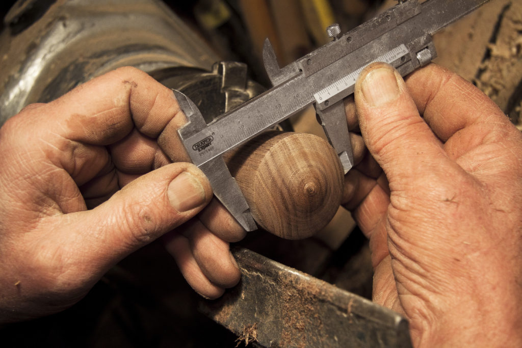 A pair of hands using calipers to measure a piece of wood, which represents the difficulty of the calculations necessary when applying for SSD coverage while self employed