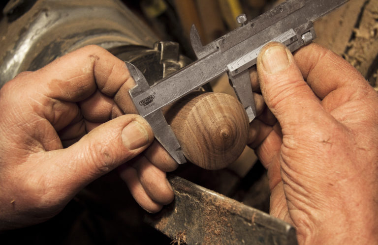 A pair of hands using calipers to measure a piece of wood, which represents the difficulty of the calculations necessary when applying for SSD coverage while self employed