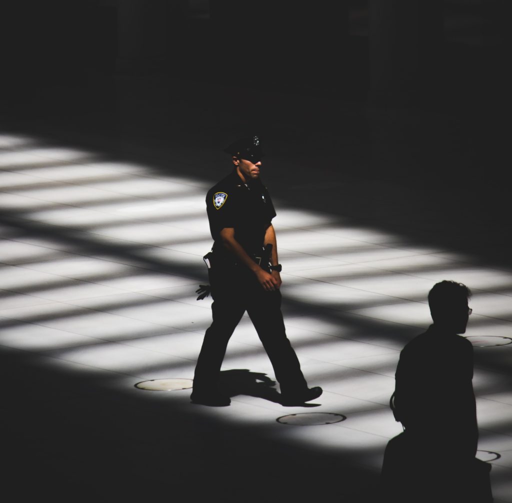 A policeman walking through slats of sunlight