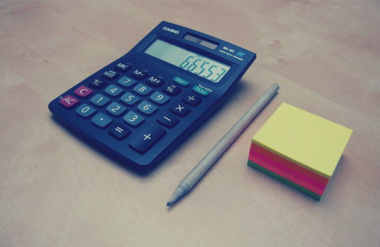 Calculator, pen and stack of post-it notes