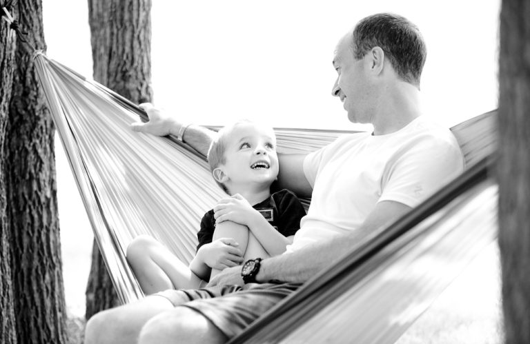 father and son sit in hammock together